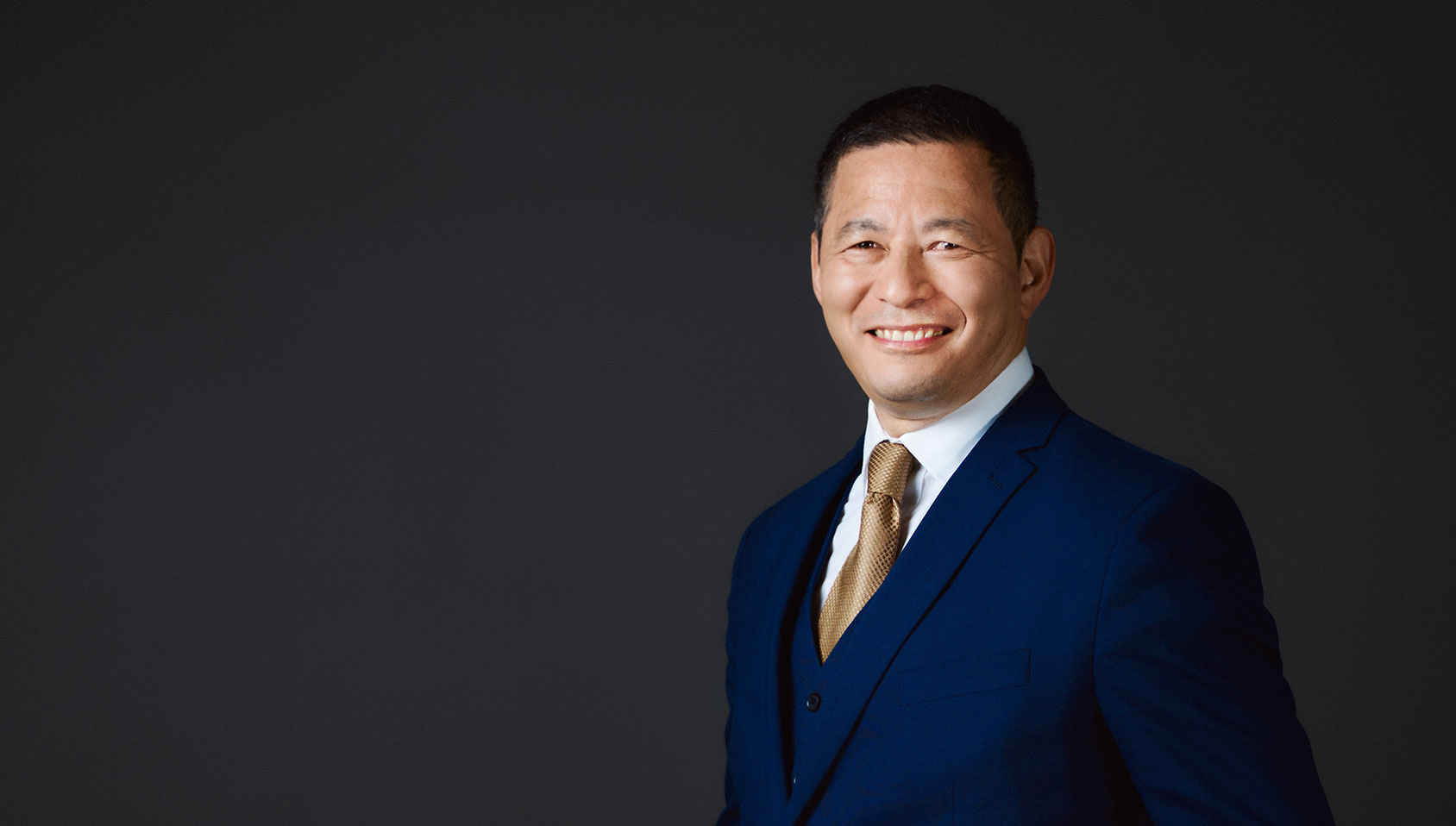 Man dressed in a blue suit, smiling