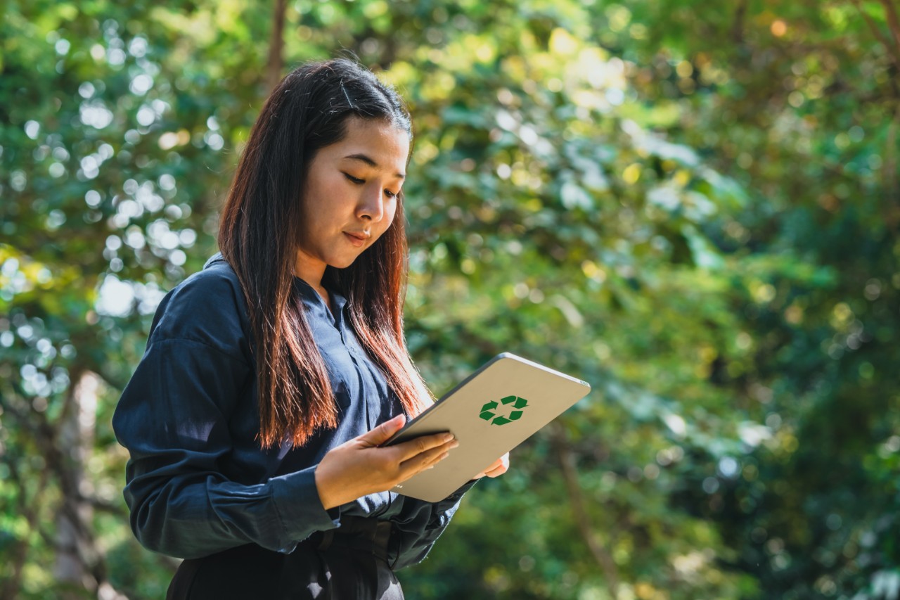 A professional woman holding a laptop with the ESG (Environment, Social, Governance) logo displayed on the screen