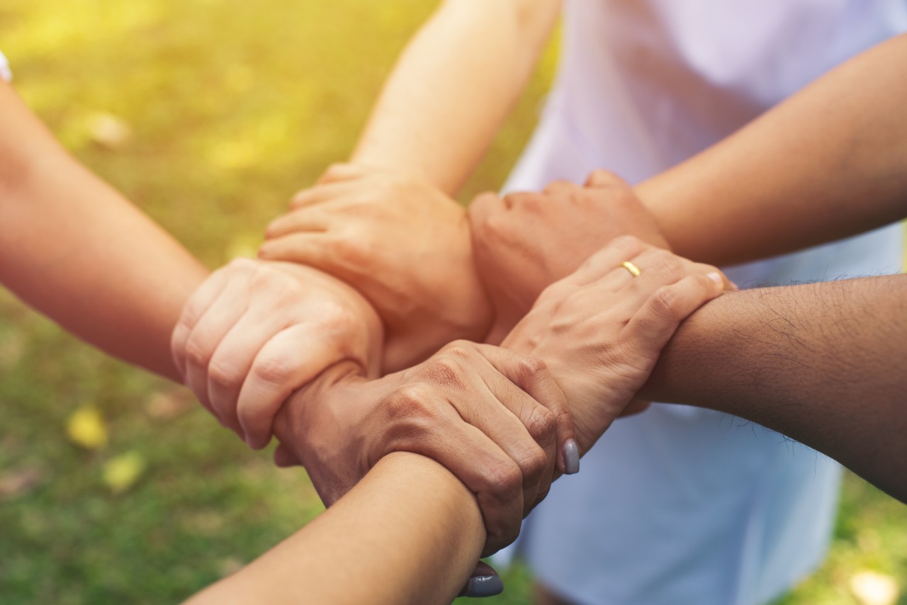 Several hands of different people standing together, forming a circle of solidarity and unity